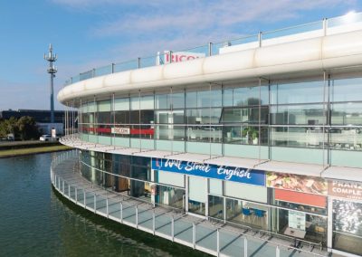 Esterno del moderno complesso commerciale e direzionale curvilineo affacciato sull'acqua realizzato da Zini Elio S.r.l.