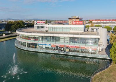 Esterno del moderno complesso commerciale e direzionale curvilineo affacciato sull'acqua realizzato da Zini Elio S.r.l.