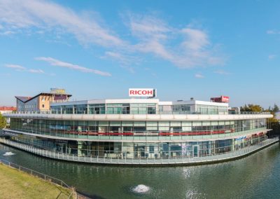 Esterno del moderno complesso commerciale e direzionale curvilineo affacciato sull'acqua realizzato da Zini Elio S.r.l.
