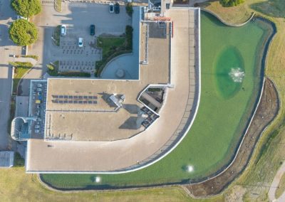 Veduta aerea zenitale del moderno edificio direzionale curvilineo lambito dal lago artificiale realizzato da Zini Elio S.r.l.
