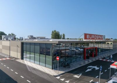 Facciata d'angolo vetrata e ingresso principale del moderno supermercato Eurospar realizzato da Zini Elio S.r.l.