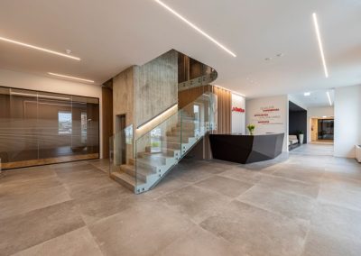 Moderna hall d'ingresso con reception e scala sospesa in vetro all'interno della sede di Zini Elio S.r.l.