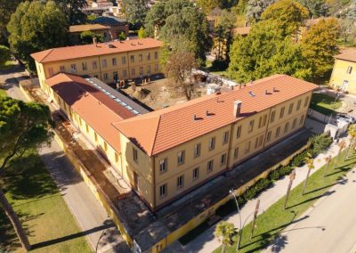 Veduta aerea di un grande edificio storico con facciata gialla e tetto in coppi ristrutturato da Zini Elio S.r.l.