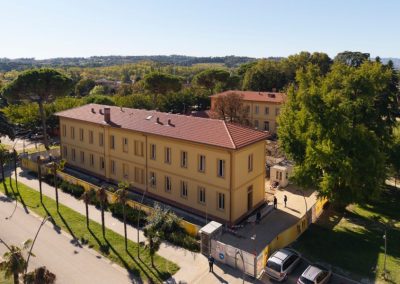 Veduta aerea di un grande edificio storico con facciata gialla e tetto in coppi ristrutturato da Zini Elio S.r.l.