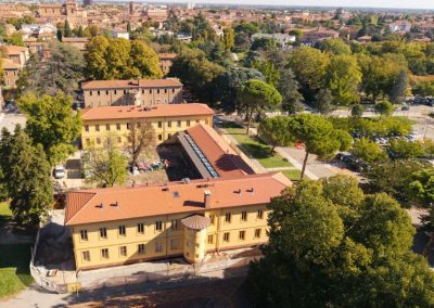 Veduta aerea di un grande edificio storico con facciata gialla e tetto in coppi ristrutturato da Zini Elio S.r.l.