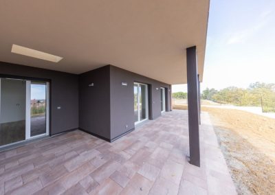 Ampio porticato esterno pavimentato con infissi moderni e pareti grigie di una villa costruita da Zini Elio S.r.l.
