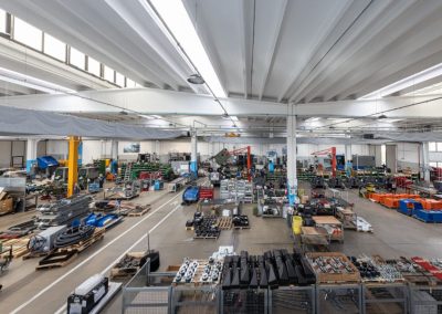Interno di un ampio capannone industriale con linee di assemblaggio e componenti meccanici ordinati
