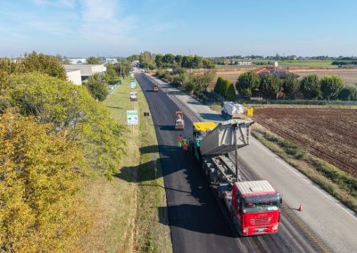 Veduta aerea di un cantiere Zini Elio S.r.l. con camion, finitrice e rulli per l'asfaltatura di una strada