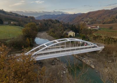 Veduta aerea di un moderno ponte stradale ad arco in acciaio bianco realizzato da Zini Elio S.r.l. sopra un fiume