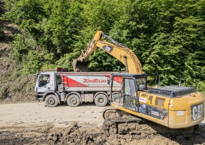 Escavatore Caterpillar carica detriti sul camion da cantiere Zini Elio S.r.l. durante il ripristino di una strada franata