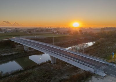 Ponte stradale in cemento armato realizzato da Zini Elio S.r.l. sopra un fiume, fotografato al tramonto